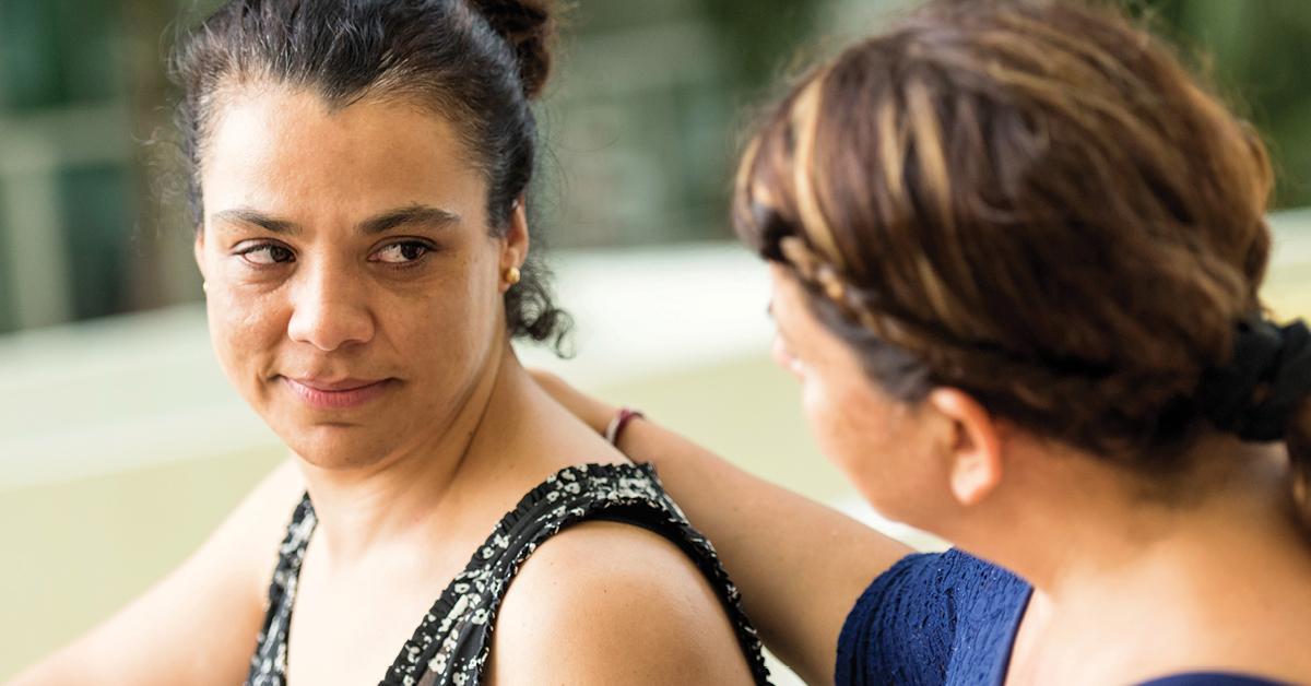 Woman With Hand on Woman's Shoulder